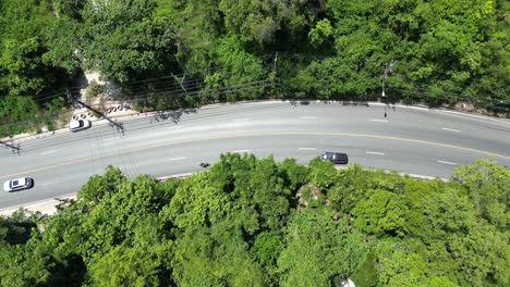 태국 코사무이 (koh samui) 의 도로의 드론 영상, 푸른 주변을 가로질러 운전하는 차량을 보여줍니다.