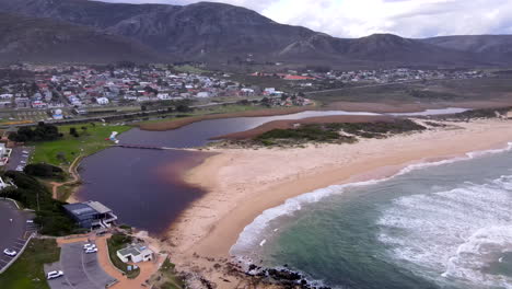 drone pullback view of lagoon and blue flag beach on scenic kleinmond coastline