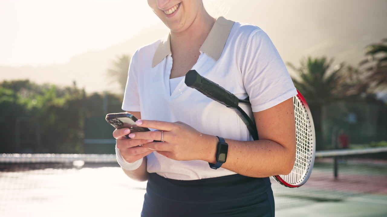Woman with tennis racket using her phone