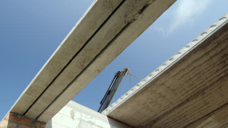 the boom of the crane installs a heavy reinforced concrete panel for the floor construction of house