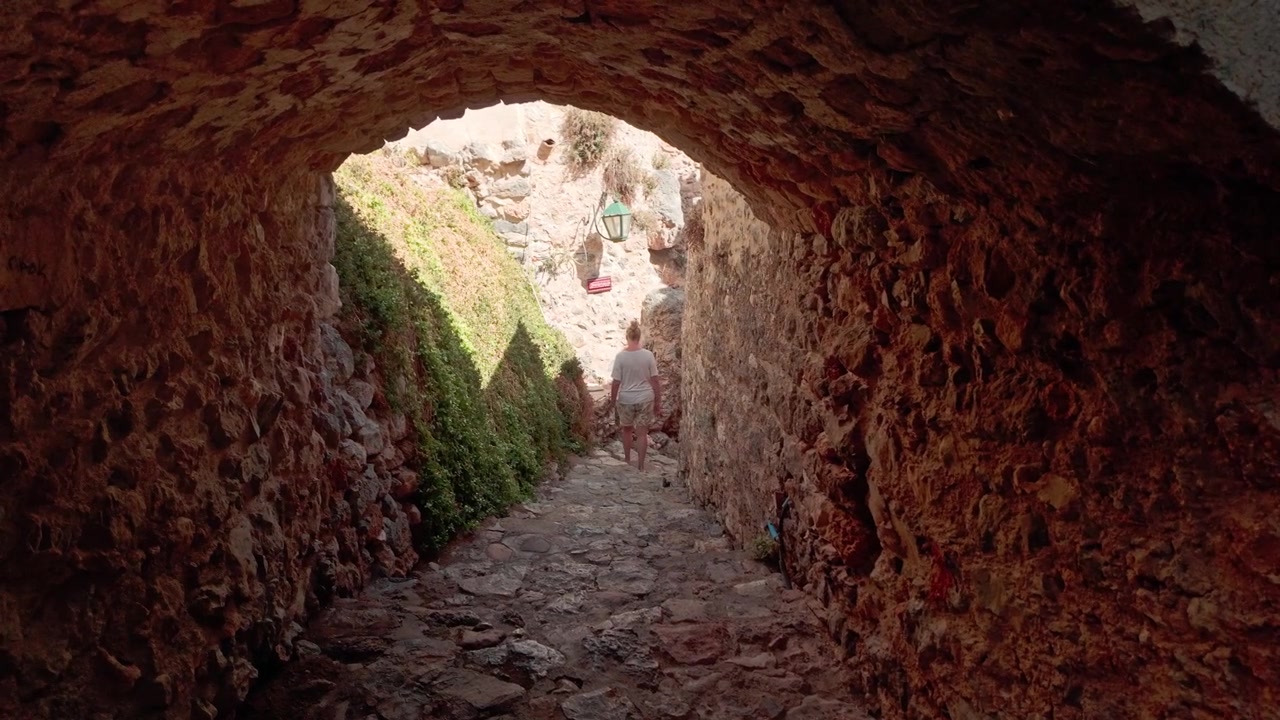 Frau als Stadtentdeckerin verirrt sich im Labyrinth der Kopfsteinpflasterstraßen von Monemvasia.