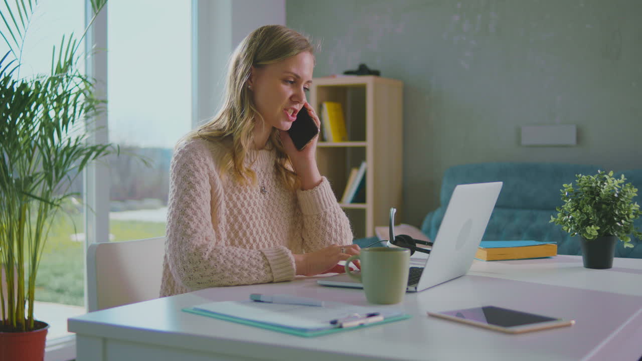 Forretningskvinde taler i telefon ved sit skrivebord