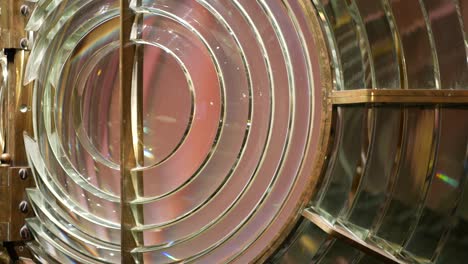 fresnel lens with brass structure, nautical lighthouse tower. detail of the glass lantern with rainbow spectrum. system of lamps and lenses to serve as a navigational aid. old sea searchlight beacon.