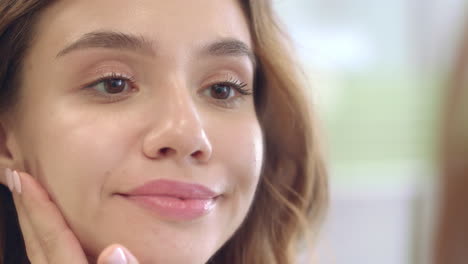 Mujer-Morena-Tocando-La-Cara-De-Piel-Suave-En-El-Espejo-Del-Baño