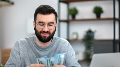feliz hombre de negocios barbudo con gafas contando dinero en efectivo dólar moneda billete en el lugar de trabajo