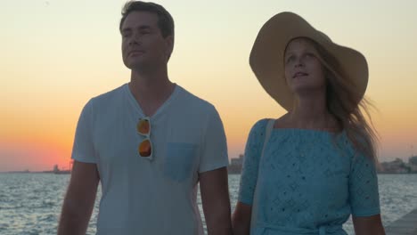 Couple-walking-on-pier-at-sunset-and-making-selfie