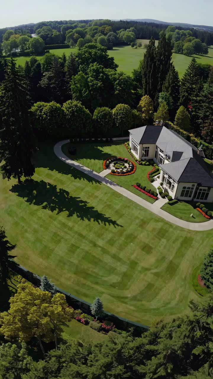 Aerial view video of a luxurious house with manicured lawns and lush trees, showcasing elegance