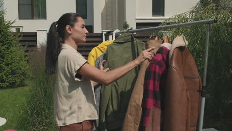 woman looking at second hand clothes at garage sale