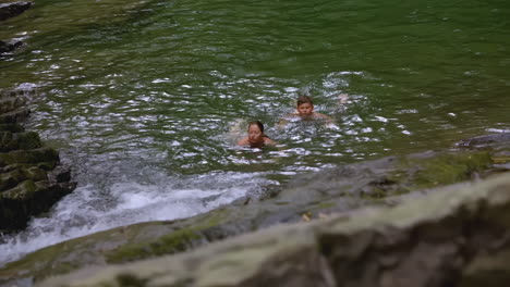 people swimming in a waterfall