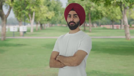 portrait of confident sikh indian man standing crossed hands in park