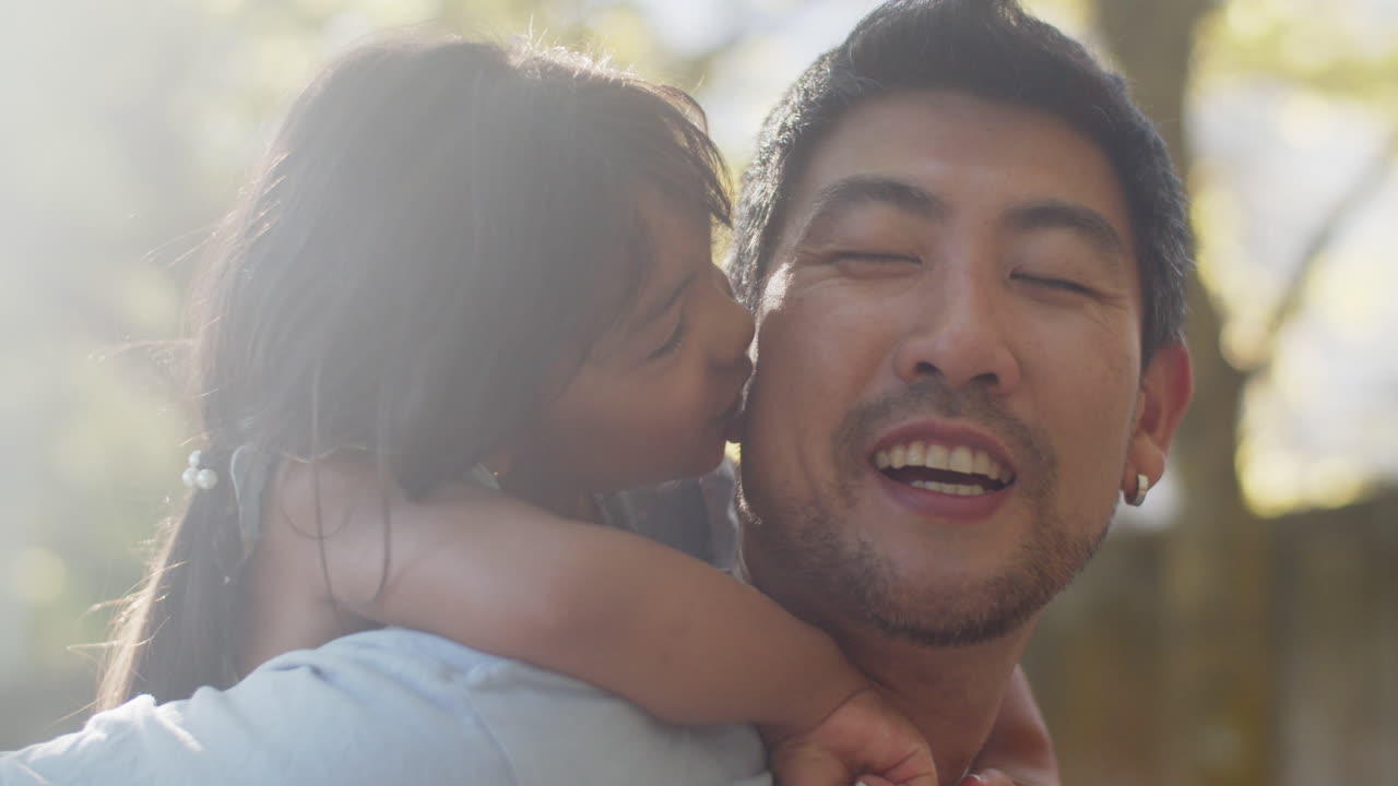 그녀의 아버지 뒤에 귀여운 아시아 소녀의 클로즈업, 미소와 그에게 키스