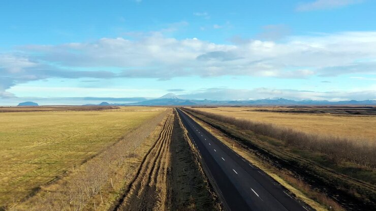 Strada a due corsie vuota, paesaggio stradale asfaltato panoramico giallo in Islanda, ripresa aerea con drone in allontanamento