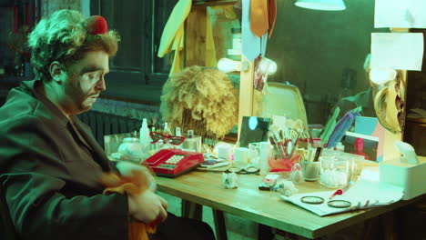 clown removing makeup in dressing room