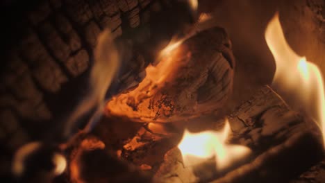 fire in a fireplace in slow motion with pieces of wood through a tiled grill