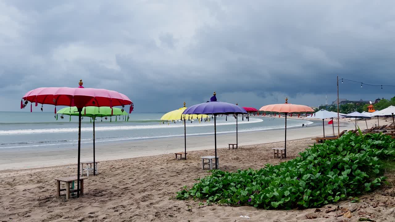 Bali’s famous Kuta Beach shows colorful umbrellas facing the ocean with dramatic skies above soft sand reflecting the island’s tropical energy and authentic coastal scenery for travelers