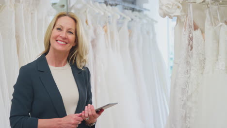 retrato de una mujer madura dueña de una tienda de vestidos de novia con una tableta digital