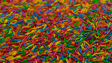 camera moves vertically thru a heap of colored sugar strands.