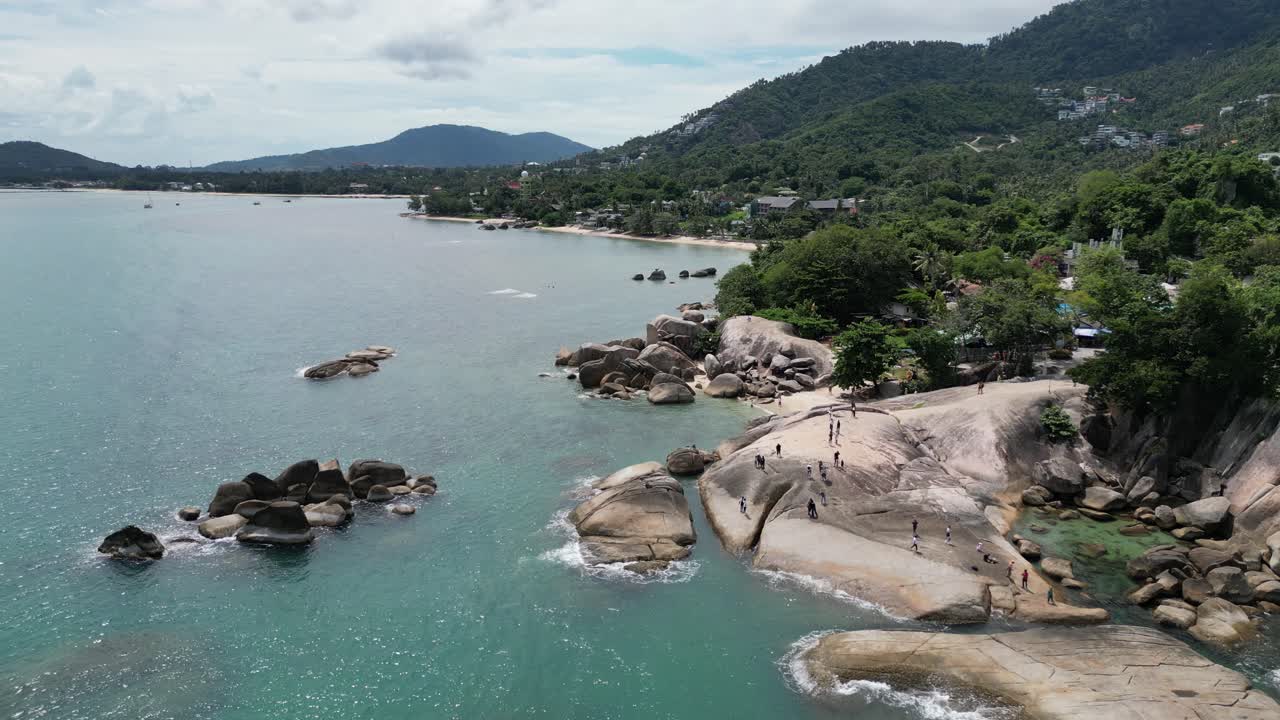 Move along shot of beach with clear turquoise water along with green hilly mountains