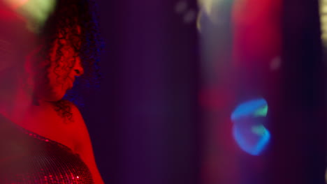 close up of young woman in nightclub bar or disco dancing with sparkling lights 2