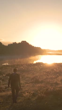 man walking at sunrise over a misty lake