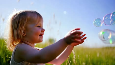 happy toddler playing with bubbles in a field