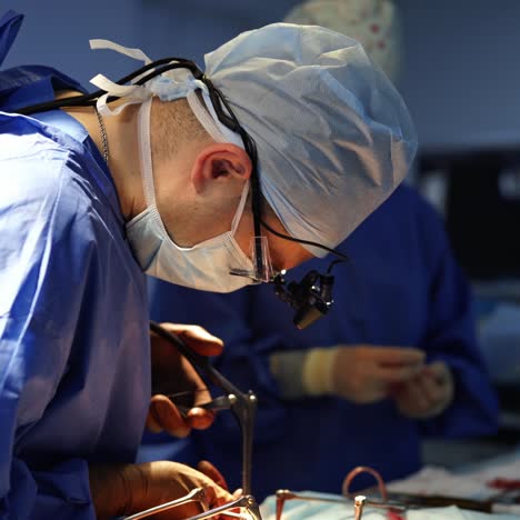 doctor together with a nurse doing surgery. professional surgeon in medical uniform and mask conducts an operation with surgical tools in the operating room