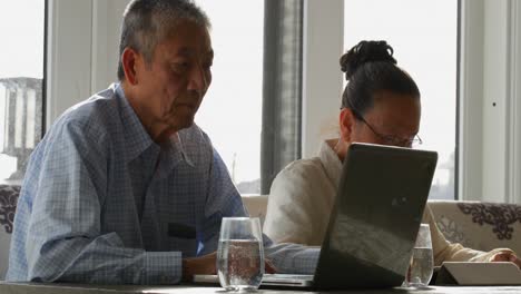 Side-view-of-old-senior-asian-couple-using-multimedia-devices-in-a-comfortable-home-4k