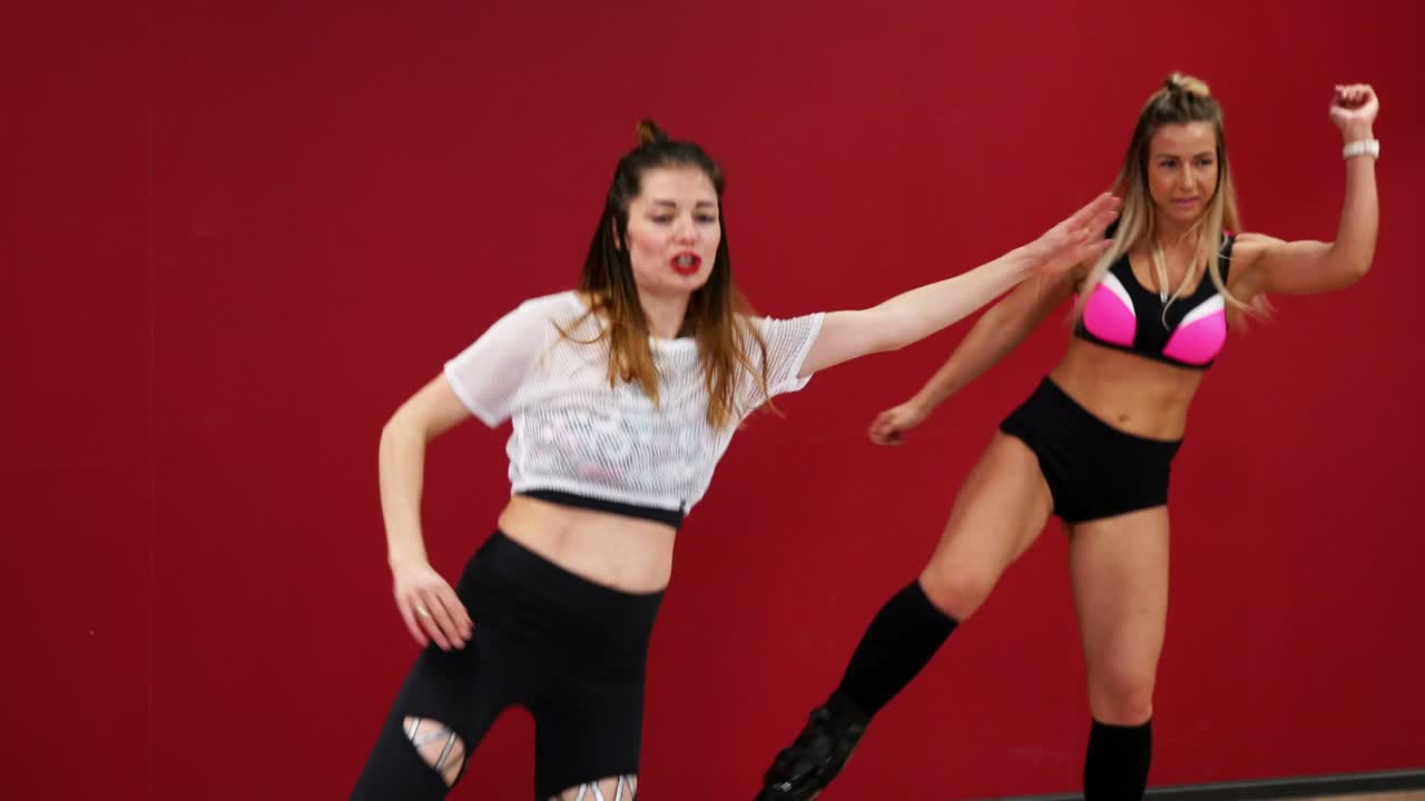 hermosa chica sexy en un fondo rojo con una pared realizar ejercicios de fitness en zapatos con un resorte. entrenamiento cardio en el estilo de salto. salto sin detenerse. quema grasa y figura sternafia con botas en los resortes. baile de fitness para la música kango