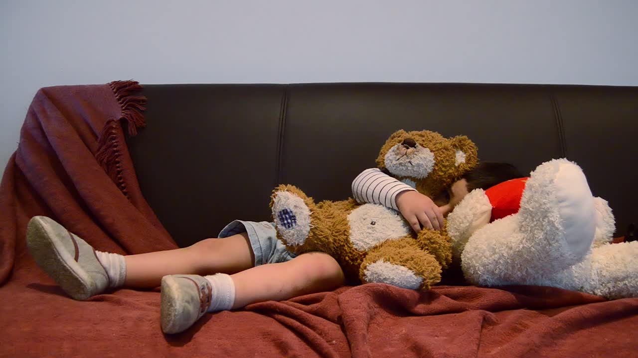 Cute tired toddler falling asleep on the couch - funny baby face expressions