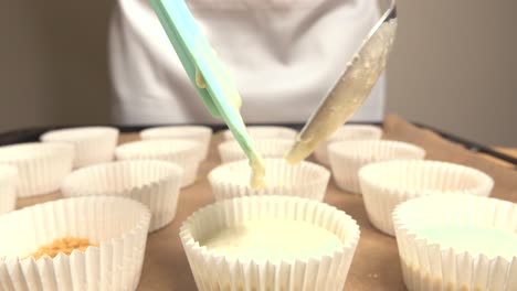 pastry chef filling molds for cheesecakes with spoon