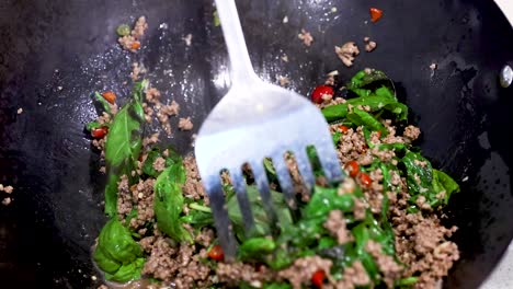 stir-frying beef and basil in a wok