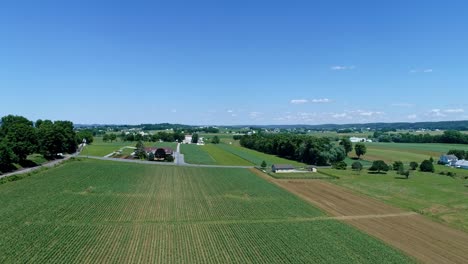 an aerial view of the farm countryside with planted fields and a single rail road track on a curve on a beautiful sunny day