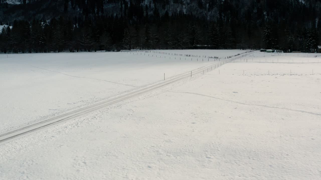 Drone flight over a snow covered winter landscape, a road is snow covered as well