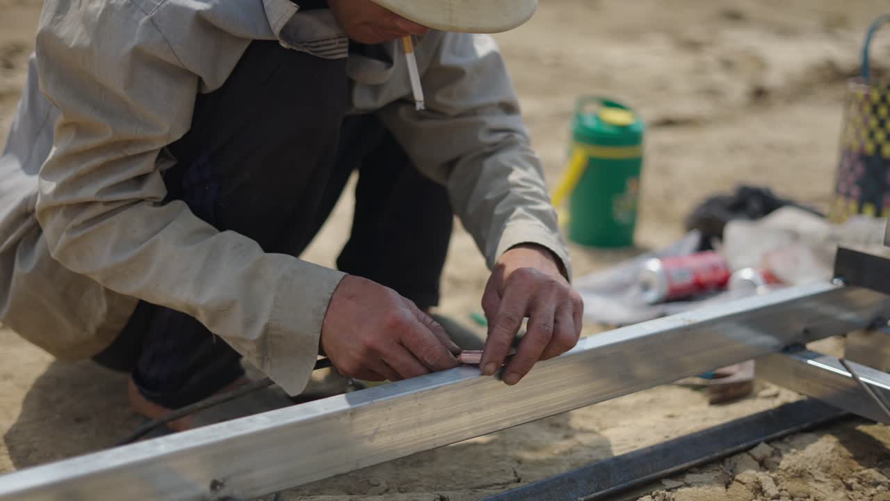 Construction worker welding metal frame outdoors