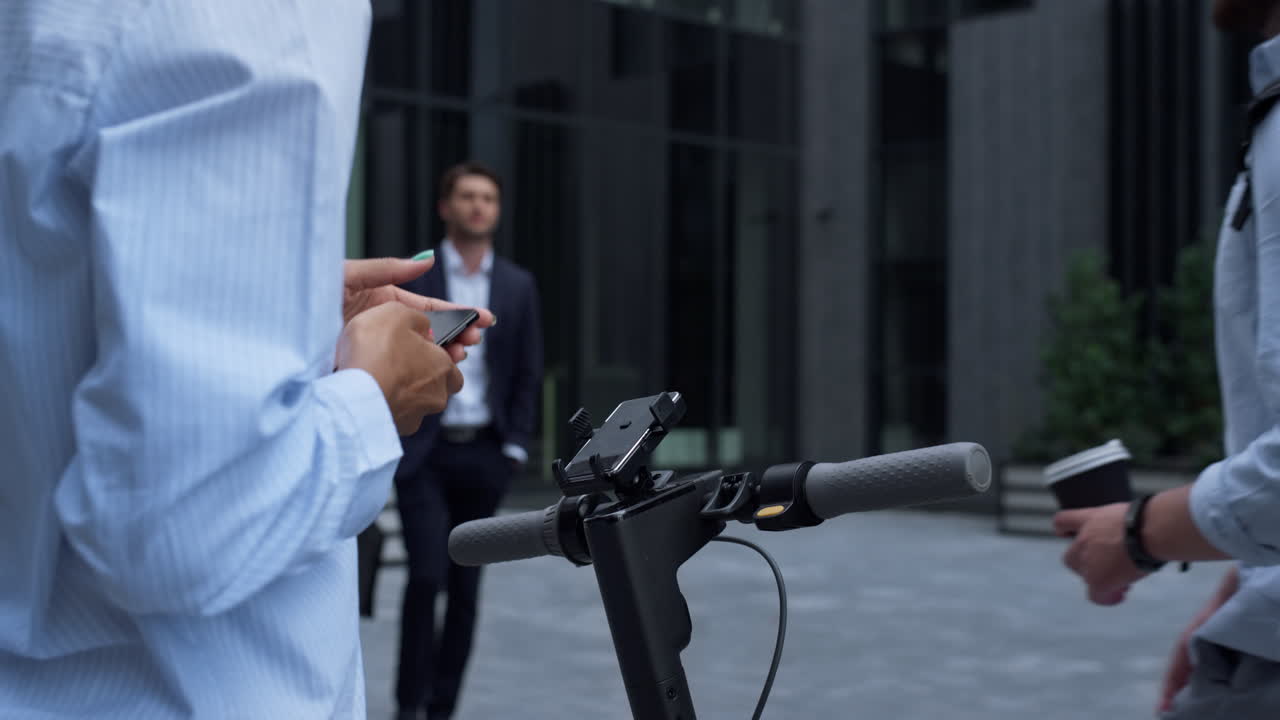 Nærbillede af hænder, der lejer el-løbehjul, holder smartphone. Koncept for bytransport.