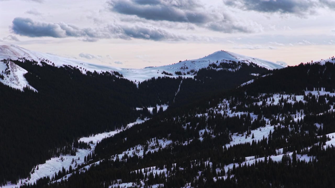Drone udara di titik awal jalur Vail Pass musim dingin, Pegunungan Rocky Colorado, Ptarmigan Hill, ski lintas alam, jalur mobil salju, puncak-puncak terjal berselimut salju, matahari terbenam, lanskap alam Hutan Nasional White River, dengan gerakan ke atas