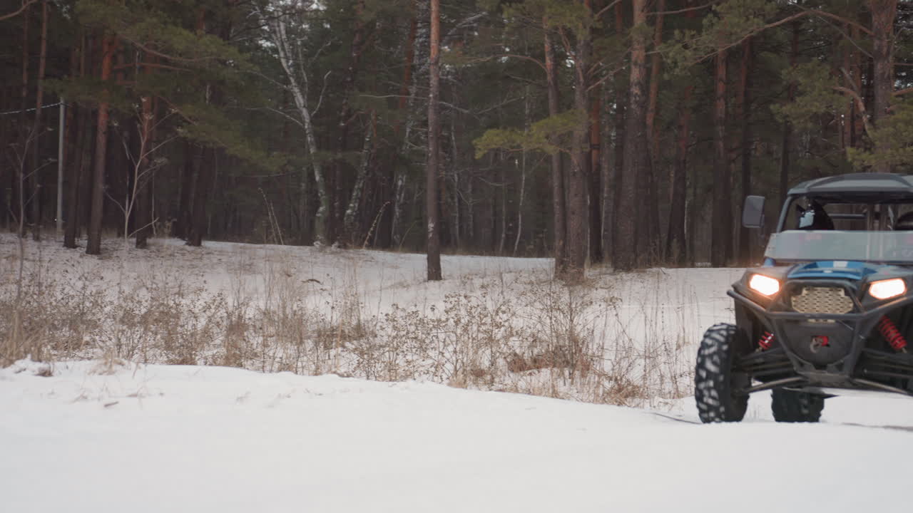 Primo piano delle ruote di un quad che tracciano un sentiero innevato, scatto tecnico intenso che mostra l'escursione della sospensione, l'aderenza del battistrada, pilota con casco concentrato, fari accesi, prestazione ad alta adrenalina