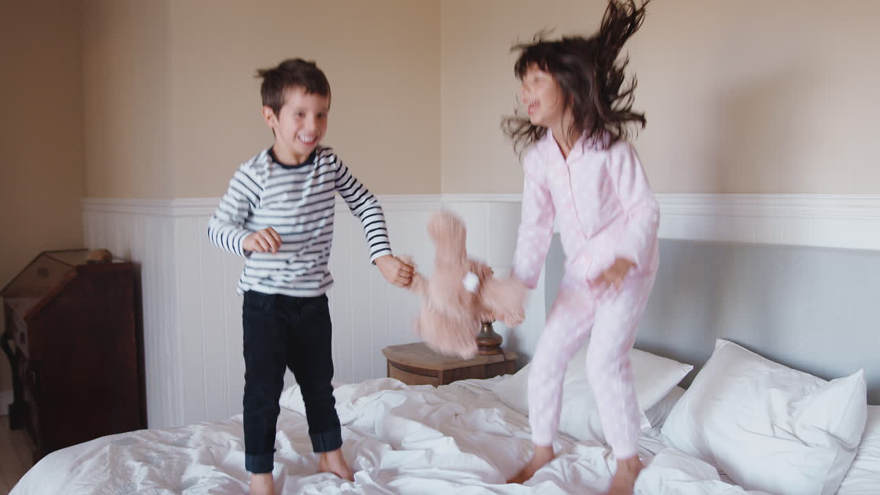 Children Having Fun Jumping And Playing On Parents Bed At Home