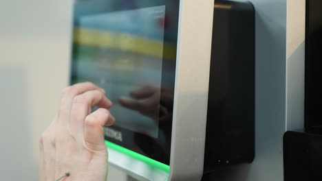 a person interacting with a touchscreen interface on a machine, providing a close-up, first-person perspective of their hand and the screen