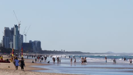 crowded beach scene with city skyline and construction