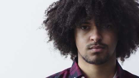 close up portrait of young mixed race man looking serious at camera with trendy afro hairstyle on white background copy space