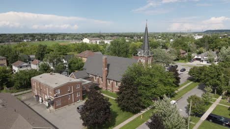 drone descend tilt up along side of st catharines church on beautiful blue sky day