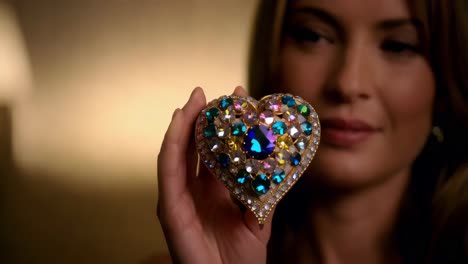 woman holding a colorful heart-shaped brooch