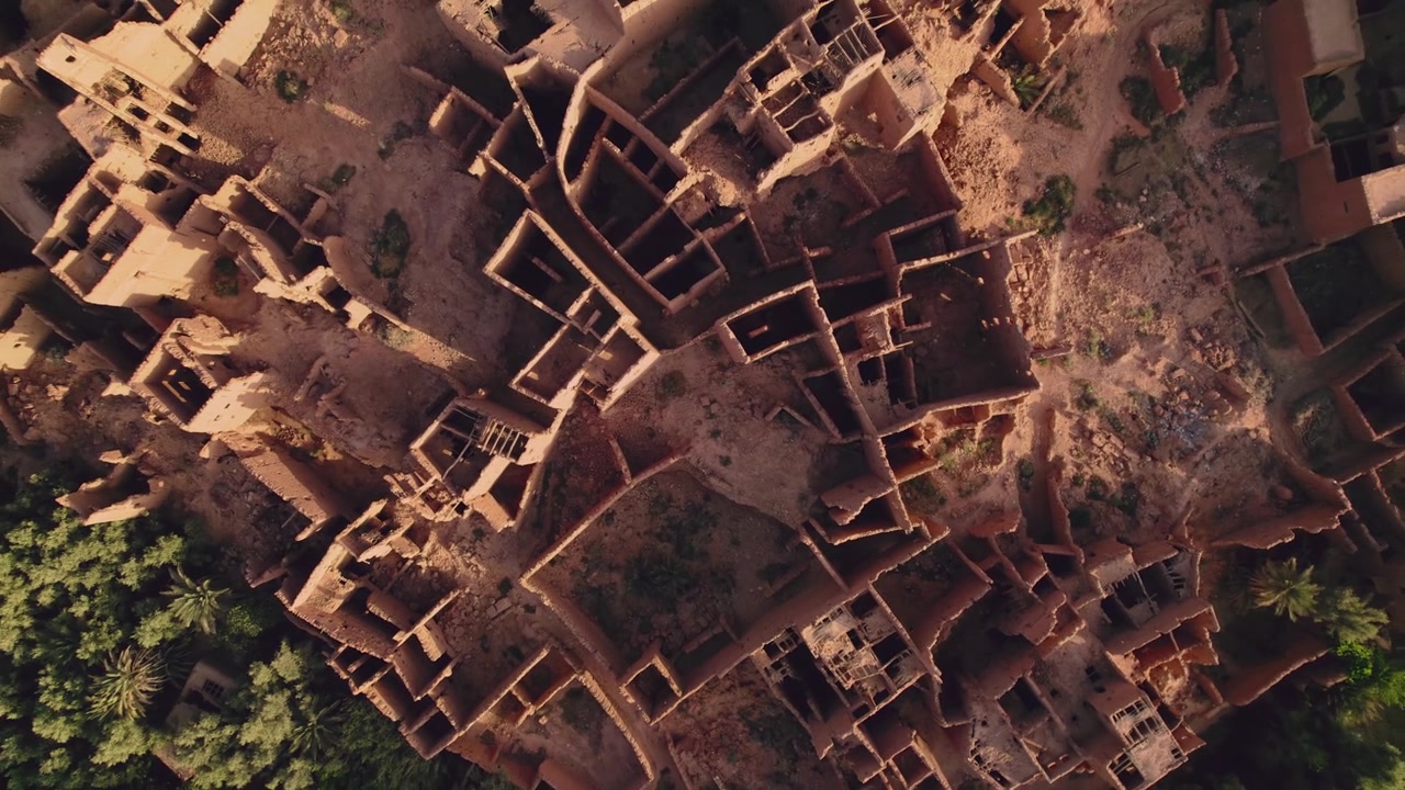 Ksar en pisé abandonné à Tinghir, Draa-Tafilalet, sud-est du Maroc, montrant une architecture de terre dense, des enceintes fortifiées et un aménagement urbain d'oasis désertique, en plan ascendant lent de haut en bas.