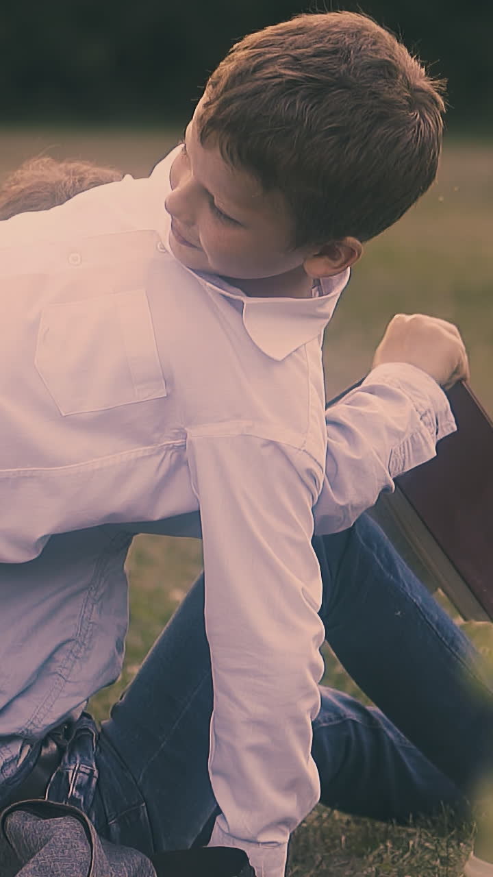schoolboy with short hair in white shirt pushes back to classmate in glasses holding textbook close view slow motion