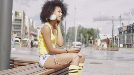 Model-in-headphones-sitting-on-bench