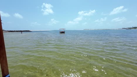 Tilt-up-slow-motion-action-camera-shot-from-on-board-of-a-small-tourist-boat-looking-out-at-crystal-clear-water-in-the-tropical-Restinga-beach-near-Barra-do-Cunhaú-in-Rio-Grande-do-Norte,-Brazil