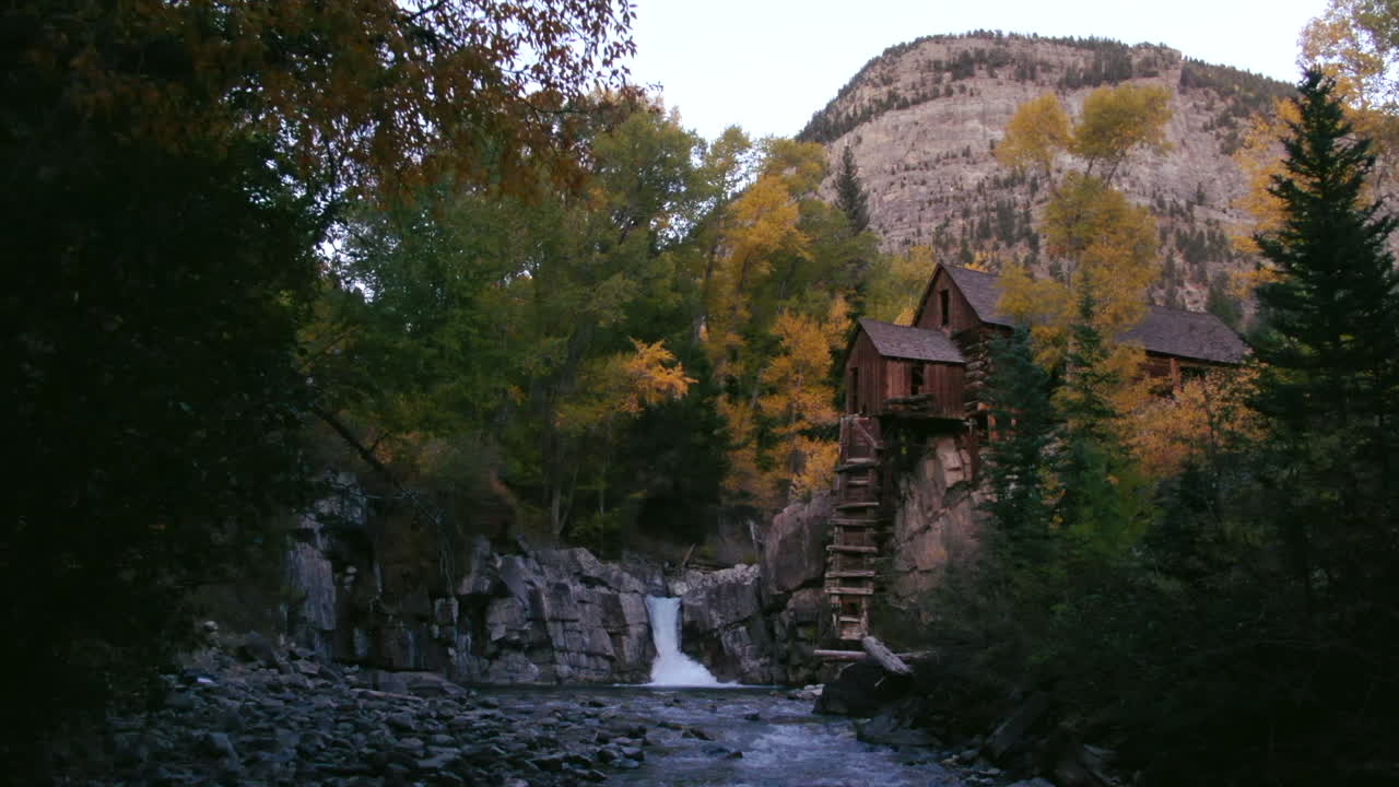 río arriba deslizador hacia adelante casa de molino de minería con cascada arroyo y río durante el otoño colores de otoño tarde abajo vista en el molino de cristal mármol colorado
