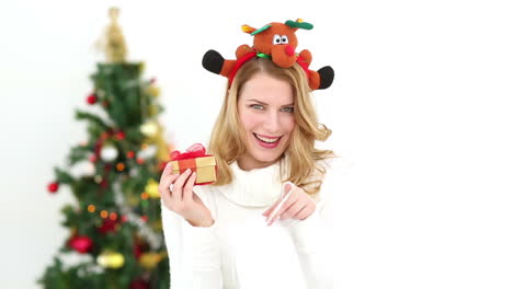 festive blonde smiling at camera showing gift