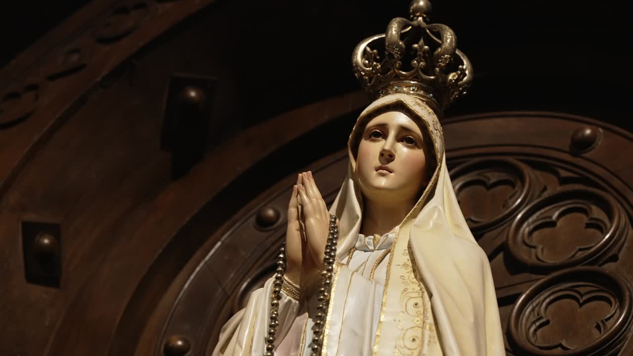 Primo piano della Vergine Maria incoronata con rosario tra le mani giunte in preghiera